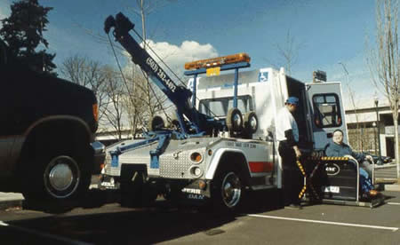 photo of a tow truck in use, with a wheelchair accessible cab getting ready to be accessed by a wheelchair user