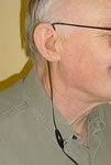 Photo of a man with the Sensocom T-Link connected to his hearing aid.